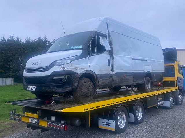 Crash-damaged Iveco van loaded on a Truck Towing tilt-tray recovery truck