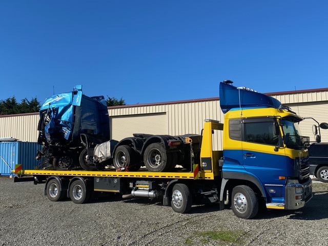 Wrecked truck cab and chassis being transported on a Truck Towing tilt-tray truck